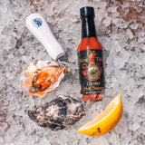 Carlsbad Aquafarm's King Tide Oyster Hot Sauce on an oyster with lemon and a shucking knife.